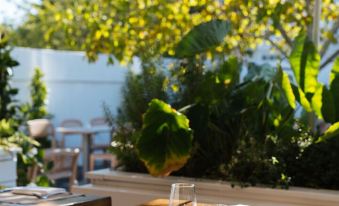 a restaurant table with wine glasses and silverware , set against a backdrop of trees and outdoor furniture at Capri Southampton