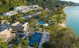 an aerial view of a resort with a pool surrounded by trees and buildings , overlooking the ocean at Banyan Tree Krabi