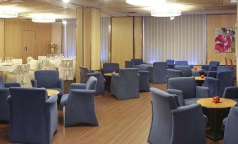 a room with several chairs and tables , some of which are covered in blue upholstery at Invisa Hotel la Cala