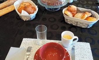 a table is set with a variety of food items , including bread , pastries , and cups at La Bastide