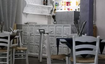 a small restaurant with white tables and chairs , a bar area , and a bar counter at Hotel Panorama
