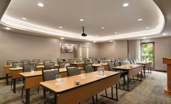 a conference room with rows of tables and chairs , a projector screen on the wall , and a window at Courtyard Middletown Goshen