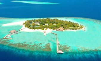 a large island in the middle of a tropical ocean , with a small boat docked at the end of the pier at Eriyadu Island Resort