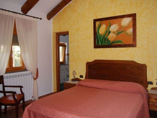 a cozy bedroom with a large bed , yellow walls , and a painting of flowers on the wall at Rabbit