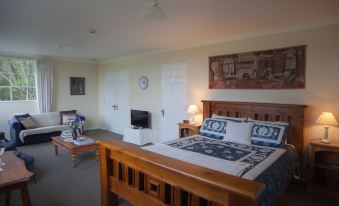 a cozy bedroom with a wooden bed , white walls , and a television mounted on the wall at The Loft Bed and Breakfast