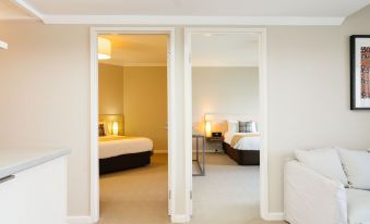 a bedroom with two beds and a doorway leading to another room , all decorated in neutral colors at The Marina Hotel - Mindarie