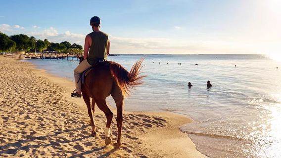 Horseback riding on the beach in southern Mauritius and swimming with horses in the sea at Le Morne