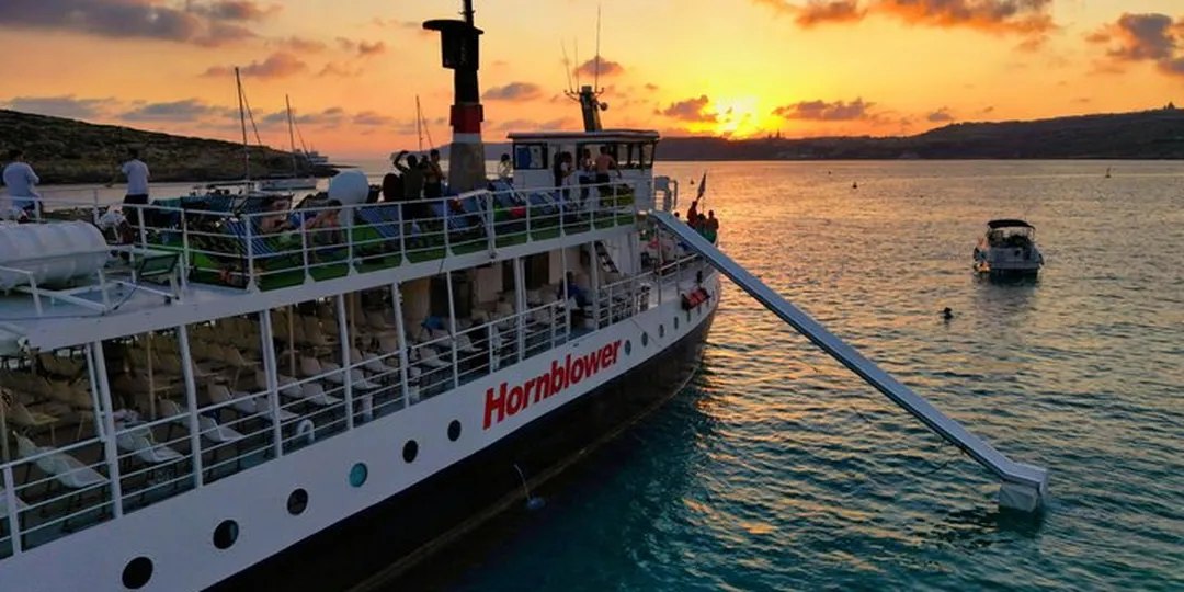 Boat moored at Comino's Blue Lagoon under a golden sky