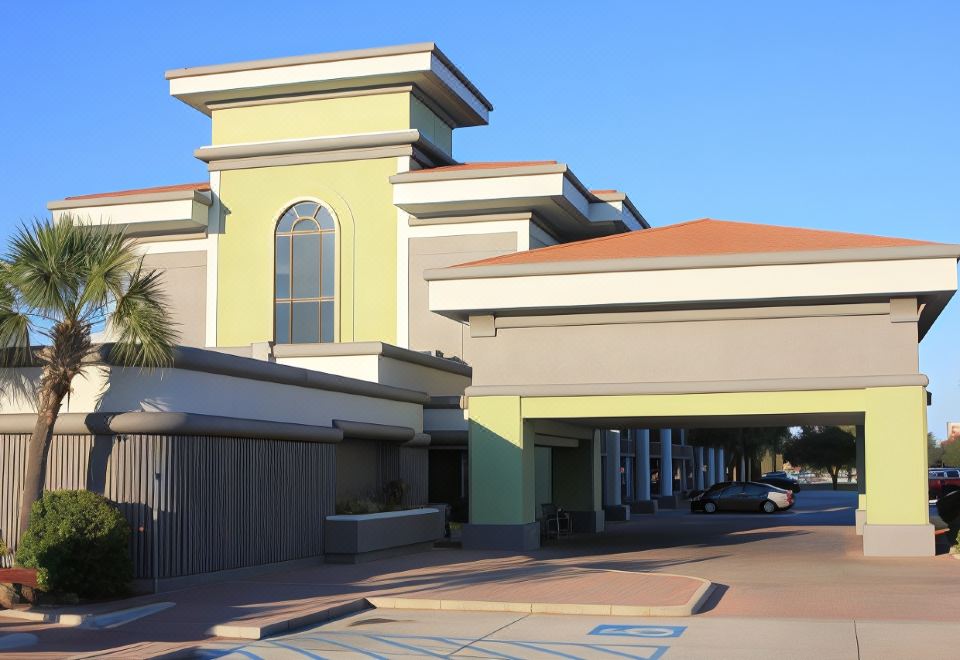 a yellow building with a garage and a brick walkway leading to it , under a clear blue sky at Holiday Home Park Central Port Arthur