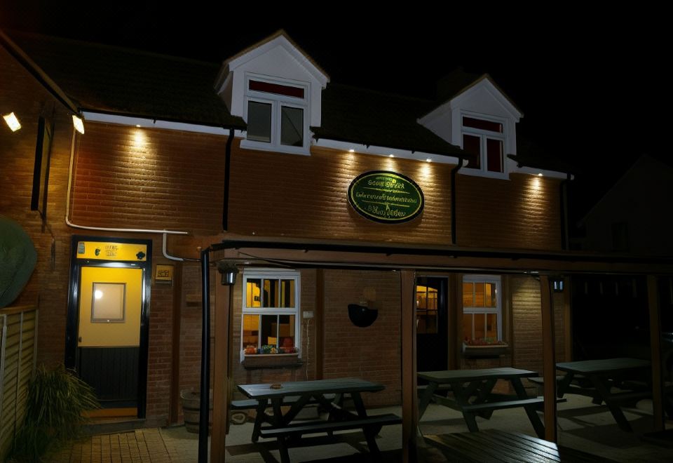 a nighttime scene of a restaurant with a sign above the entrance and outdoor seating area at The Foxham