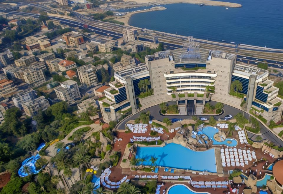 an aerial view of a city with a large hotel complex surrounded by water and roads at Le Royal Hotel - Beirut