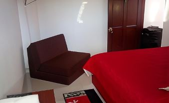 a bedroom with a red bed , brown chair , and a tv mounted on the wall at Montesion