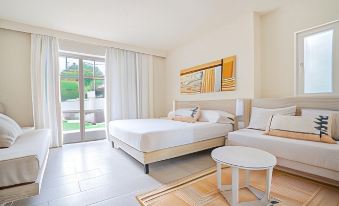 a modern hotel room with a large bed , white furniture , and a balcony door leading to an outdoor area at La Coluccia