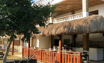 a thatched - roof building with a balcony , surrounded by trees and a tree - lined street , and several bicycles parked nearby at Scent of Green Papaya