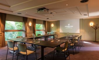 a conference room set up for a meeting , with chairs arranged in rows and a projector on the wall at Les Etangs de Corot