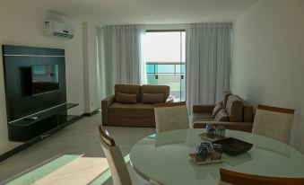 a modern living room with a glass dining table , brown leather couches , and a large window overlooking the ocean at Sophia II Residence Inn