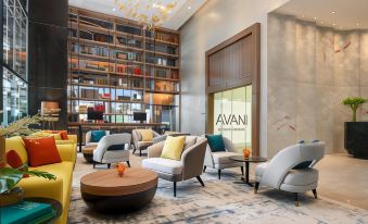 The lobby is an elegant room with large windows, chairs, and tables in the center at Avani Sukhumvit Bangkok Hotel