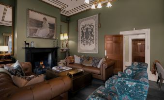 a spacious living room with a large leather couch , a wooden coffee table , and a fireplace at Quamby Estate