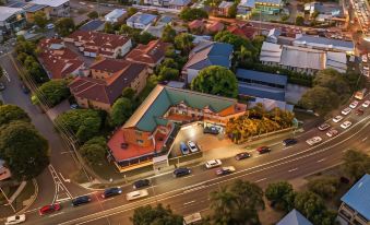 a bird 's eye view of a city street with cars , buildings , and trees at night at Airport Clayfield Motel