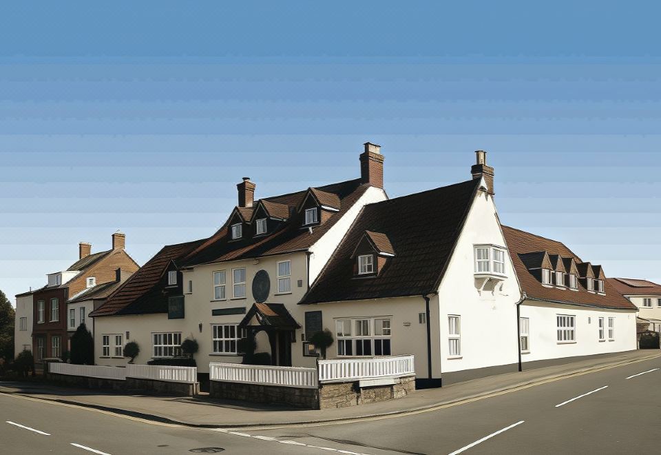 a large , white house with a brown roof and chimneys is situated on the side of a road at Malt House