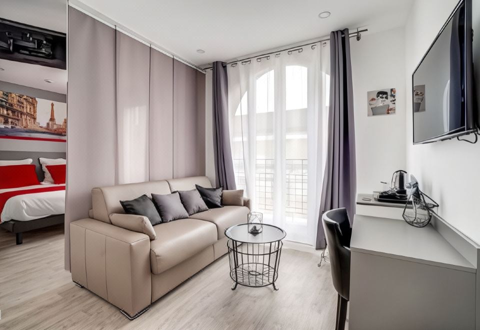 a modern living room with a couch , coffee table , and television is shown next to a window at Paris Hotel