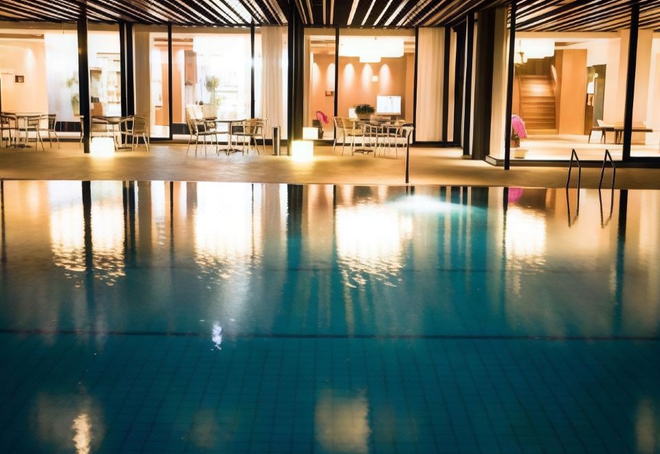 a large indoor swimming pool surrounded by glass walls , with several lounge chairs placed around the pool area at Hotel Fuji