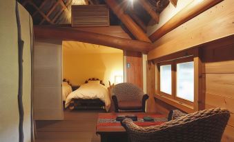 a cozy living room with wooden walls , a couch , and a chair in front of a window at Shouen