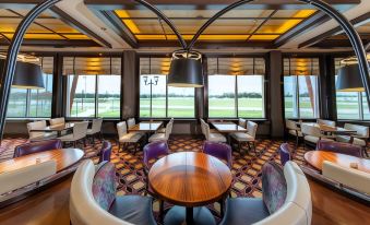 a modern lounge area with purple and white chairs , a round table , and large windows at Delta Downs Racetrack Casino Hotel