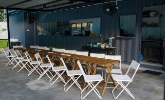 a long wooden table surrounded by white chairs in a room with a blue wall at Sarang by the Brook