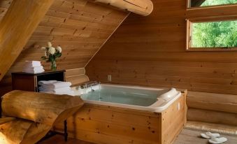 a wooden bathtub is filled with water in a cozy , rustic bathroom with a sloped ceiling at Justin Trails Resort