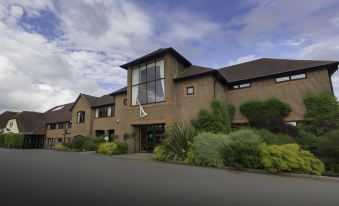 a modern building with large windows and a gray roof , surrounded by lush greenery and a clear blue sky at Dale Hill Hotel