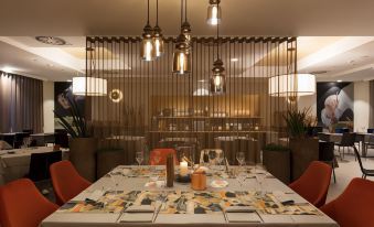 a dining table with a white tablecloth and wine glasses is set up in a restaurant at Winter Garden Hotel Bergamo Airport