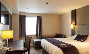 a hotel room with a bed , desk , and chair , along with a window and a window sill at Premier Inn Trowbridge