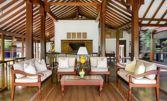 a spacious living room with wooden furniture , including chairs and a couch , arranged around a coffee table at Uga Ulagalla - Anuradhapura