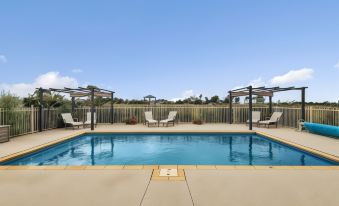 an outdoor pool surrounded by a fence , with several lounge chairs and umbrellas placed around it at The Oxley Estate
