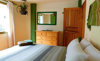 a bedroom with a bed , dresser , and mirror , as well as a door leading to another room at La Casa Verde
