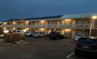 a parking lot with several cars parked in front of an apartment building at dusk at Motel Goolwa