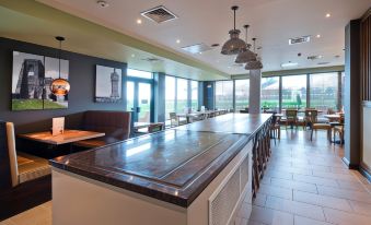 a modern kitchen with an island counter , hanging lights , and large windows offering views of the outside at Thirsk