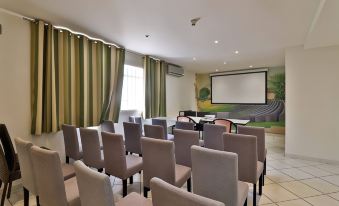 a conference room with rows of chairs arranged in front of a projector screen , ready for a meeting or presentation at Hôtel Restaurant de la Mer