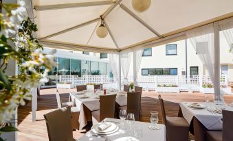 a dining room with tables and chairs set up for a meal , under a large white canopy at Hotel Concorde