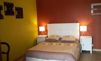 a cozy bedroom with a white bed , yellow walls , and a lamp on the nightstand at La Roque