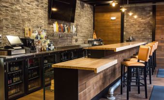 a modern bar with wooden counter , multiple stools , and a tv mounted on the wall at Cobblestone Hotel & Suites - Chippewa Falls