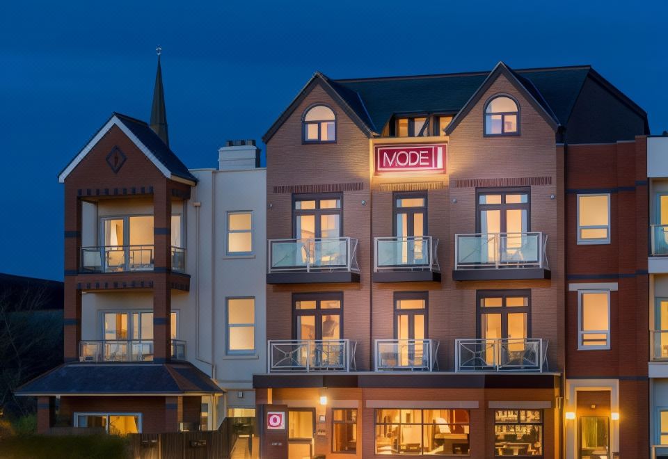"a building with a sign that says "" hotel "" is lit up at night , surrounded by trees and cars" at Mode Hotel St Annes
