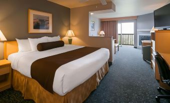 a large bed with a brown blanket and white sheets is in a hotel room at Lighthouse Suites Inn