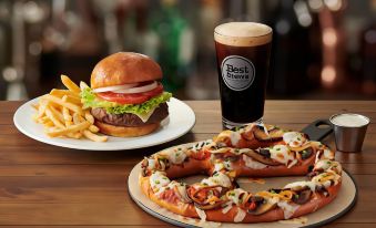 a dining table with a plate of pizza and a hamburger , accompanied by a glass of beer at Four Points by Sheraton Brunswick