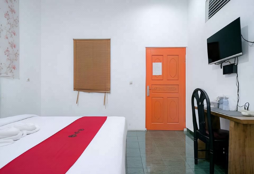 a hotel room with a red bed , white walls , and a tv on the wall at Mason Residence Syariah Ciawi