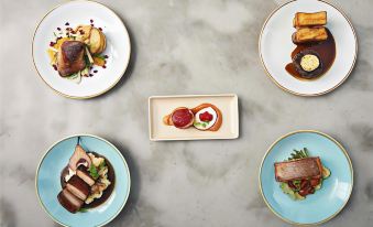 a table is set with four plates of various food items , including meat and vegetables at Sage Melbourne Ringwood