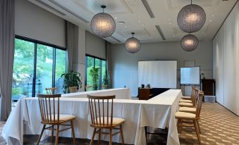 a conference room with a long table , chairs , and large windows , decorated with hanging lights and potted plants at The Retreat