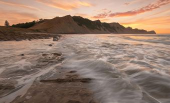 a rocky shoreline with waves crashing against the rocks , and a beautiful sunset in the background at Motel Oasis