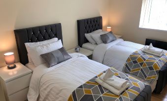 a room with two beds , one on the left and one on the right , both covered in white sheets at Green Apartments